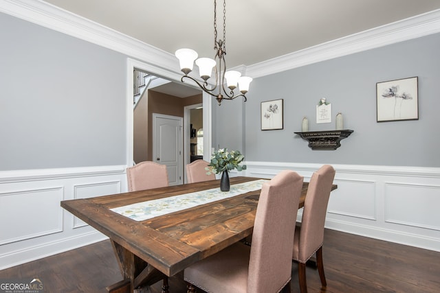 dining room featuring an inviting chandelier, a decorative wall, dark wood-type flooring, and crown molding