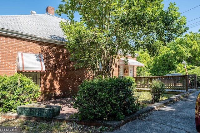 738 Liberty St, Macon, GA 31201 - view of property exterior featuring brick siding, a wooden deck, a chimney, and a shingled roof