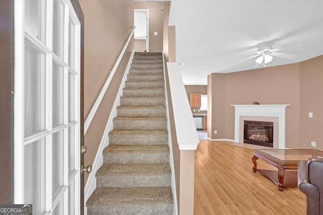 200 Arrowhead Ln, Canton, GA 30114 - stairs with ceiling fan, a fireplace with flush hearth, wood finished floors, and baseboards