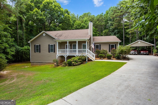 view of front of house featuring covered porch, a front yard, a detached carport, driveway, and a chimney