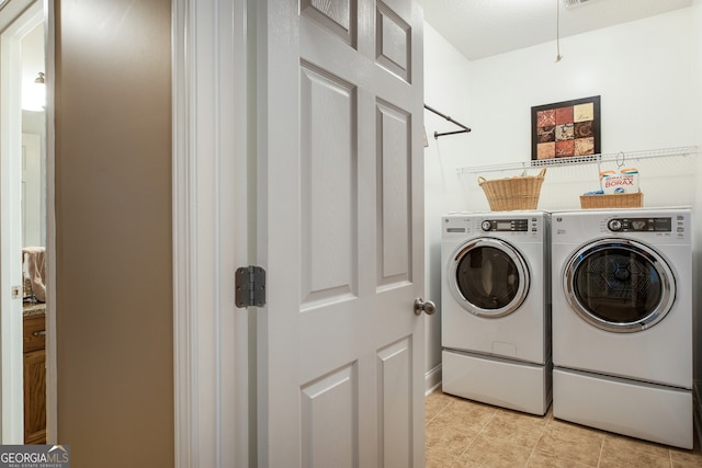 laundry room with washing machine and dryer, light tile patterned floors, and baseboards