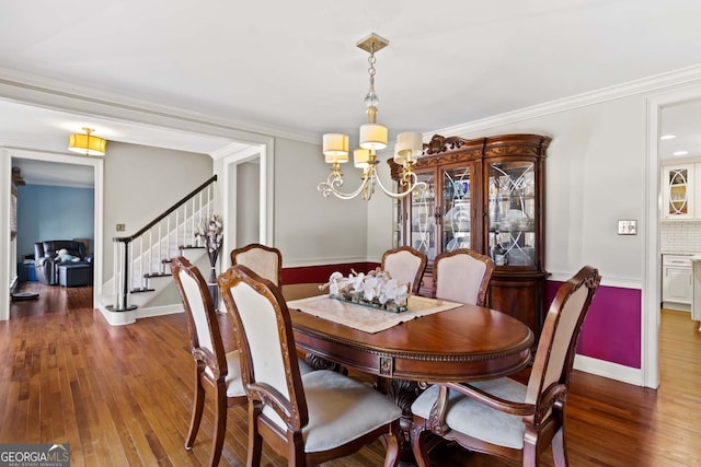 dining area featuring baseboards, an inviting chandelier, ornamental molding, stairs, and hardwood / wood-style flooring