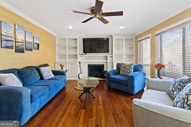 living room featuring crown molding, wood finished floors, ceiling fan, and a brick fireplace