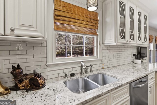 kitchen with decorative backsplash, dishwasher, a sink, and glass insert cabinets