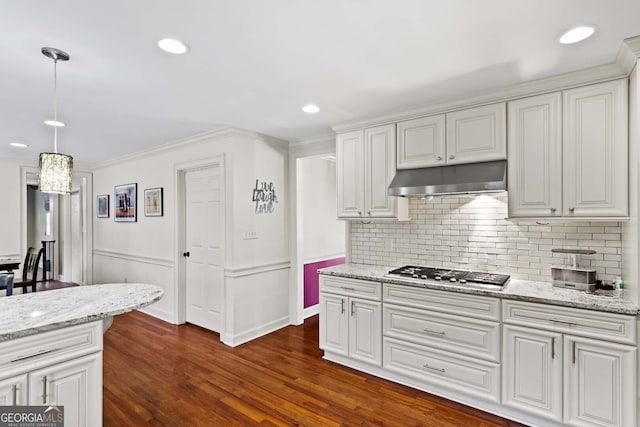 kitchen with tasteful backsplash, under cabinet range hood, dark wood-type flooring, pendant lighting, and stainless steel gas cooktop