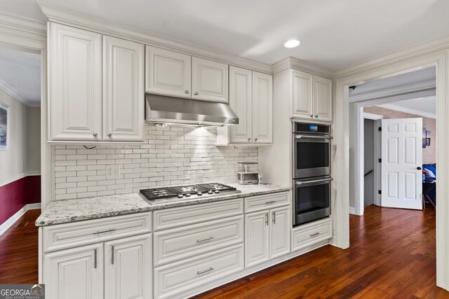 kitchen featuring dark wood-style flooring, baseboards, stainless steel appliances, and under cabinet range hood