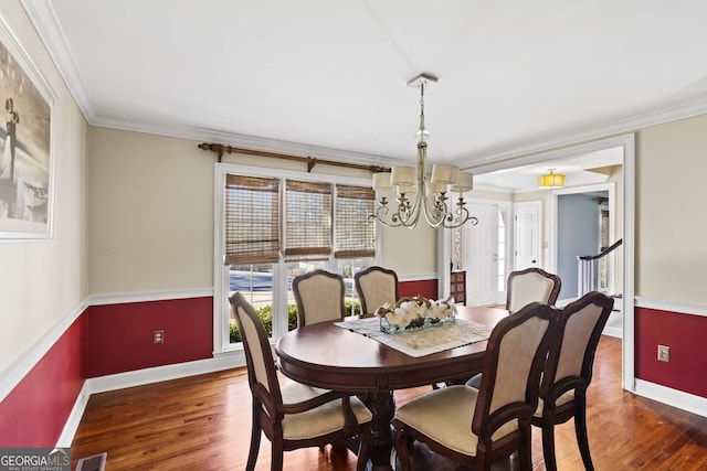 dining space featuring crown molding, visible vents, wood finished floors, a notable chandelier, and baseboards