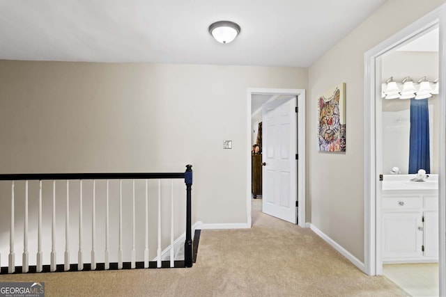 hall with baseboards, an upstairs landing, and light carpet