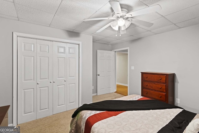 bedroom with a paneled ceiling, a closet, a ceiling fan, and carpet