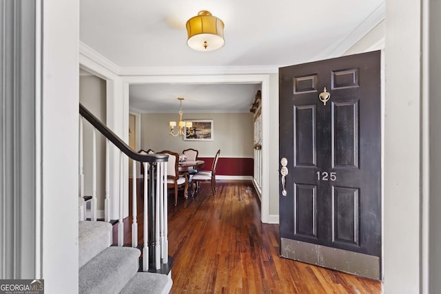 entryway featuring ornamental molding, a chandelier, wood finished floors, stairs, and baseboards
