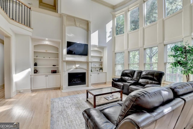 1806 Royal Troon Ct, Duluth, GA 30097 - living area with a towering ceiling, light wood finished floors, a premium fireplace, built in features, and ornamental molding