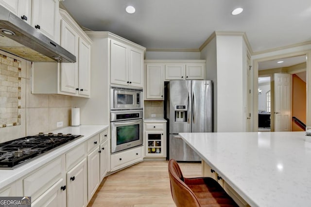 1806 Royal Troon Ct, Duluth, GA 30097 - kitchen with appliances with stainless steel finishes, under cabinet range hood, tasteful backsplash, white cabinetry, and ornamental molding