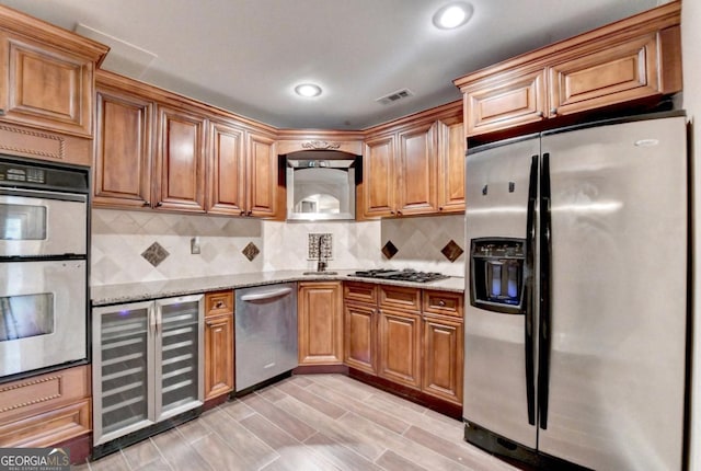 1806 Royal Troon Ct, Duluth, GA 30097 - kitchen featuring appliances with stainless steel finishes, wine cooler, light stone countertops, backsplash, and brown cabinetry