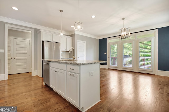 kitchen featuring white cabinets, baseboards, a sink, appliances with stainless steel finishes, and a chandelier
