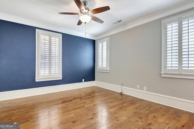 spare room with baseboards, a ceiling fan, crown molding, visible vents, and wood finished floors
