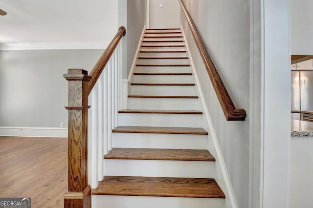 staircase featuring baseboards, ornamental molding, and wood finished floors
