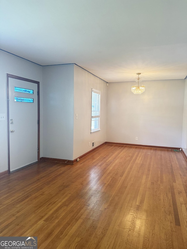 6718 Delta Dr, Riverdale, GA 30274 - unfurnished living room with baseboards, an inviting chandelier, and wood finished floors