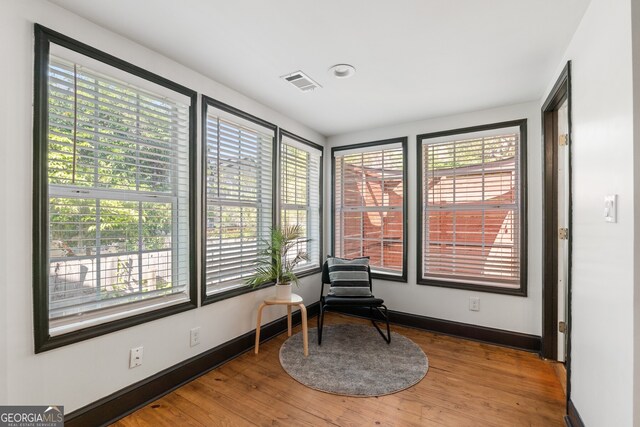 sitting room featuring wood finished floors, a wealth of natural light, and visible vents