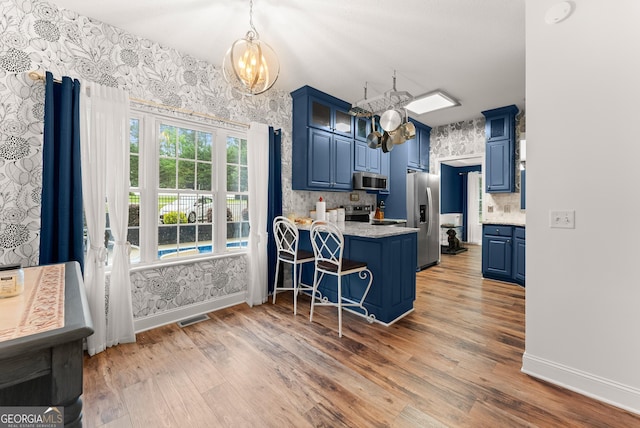 791 Thornwood Cir, Mount Airy, GA 30563 - kitchen with blue cabinets, stainless steel appliances, a chandelier, a peninsula, and wallpapered walls