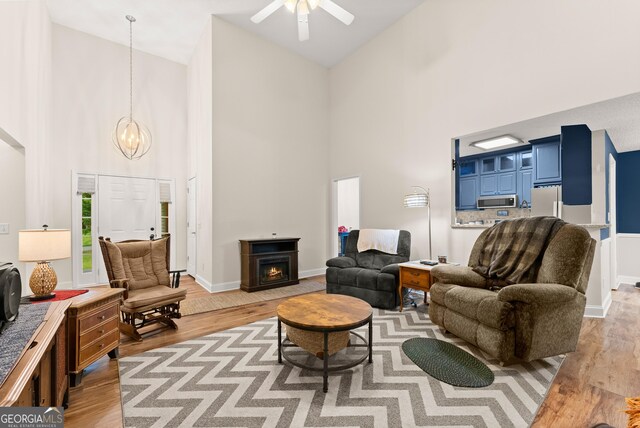 791 Thornwood Cir, Mount Airy, GA 30563 - living area featuring high vaulted ceiling, light wood-style floors, a chandelier, a ceiling fan, and a lit fireplace