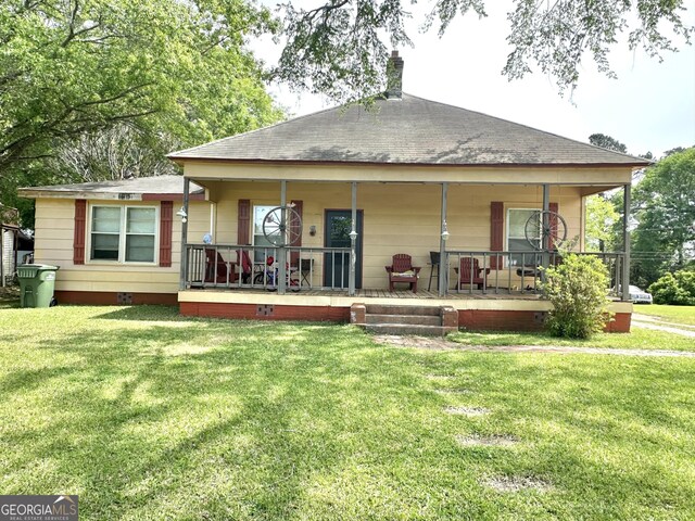 rear view of property featuring a porch, a chimney, and a lawn