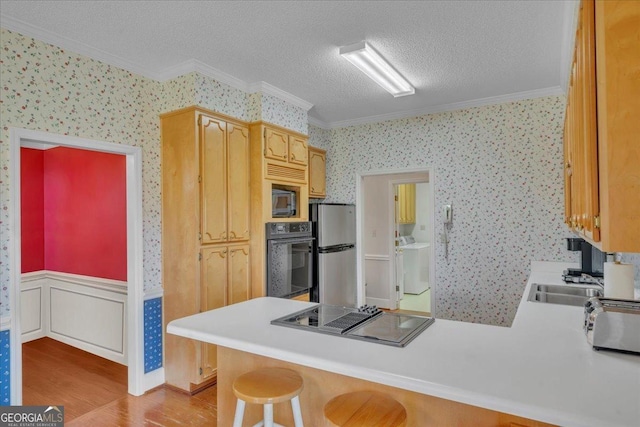 485 Fussell Rd, Leesburg, GA 31763 - kitchen with ornamental molding, light wood-style floors, a peninsula, black appliances, and wallpapered walls