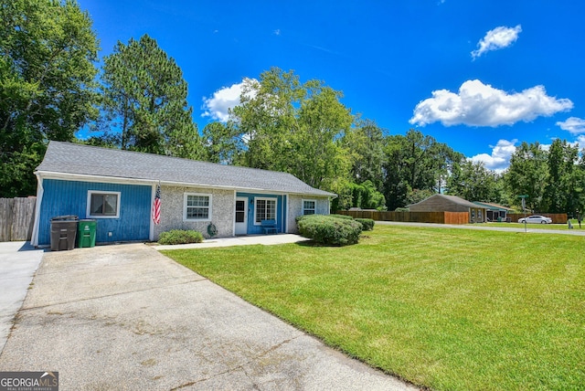 ranch-style home with driveway, fence, and a front lawn