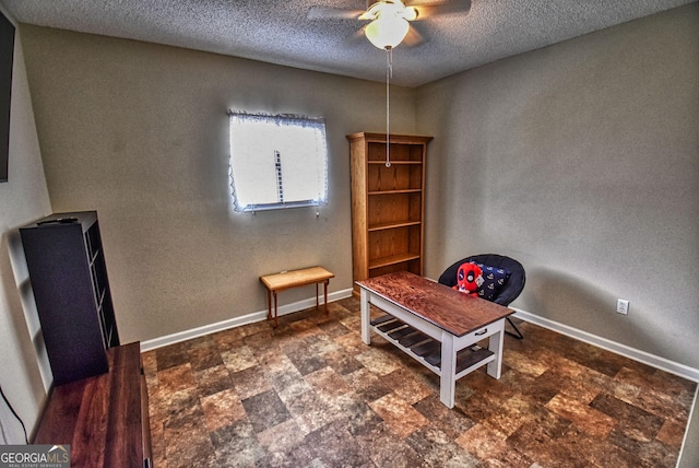 living area with stone finish flooring, baseboards, a textured ceiling, and a ceiling fan
