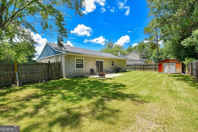 rear view of house with a shed, a patio area, a fenced backyard, an outdoor fire pit, and a lawn
