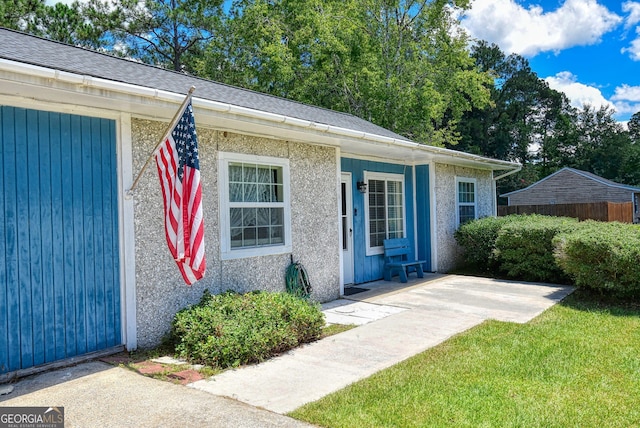 view of exterior entry with a yard and stucco siding