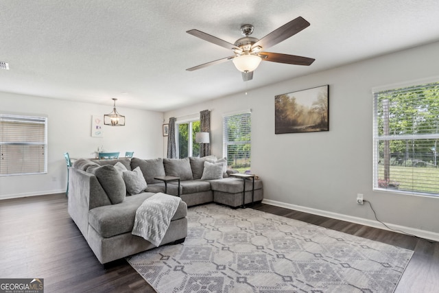 living area featuring wood finished floors, ceiling fan with notable chandelier, and baseboards