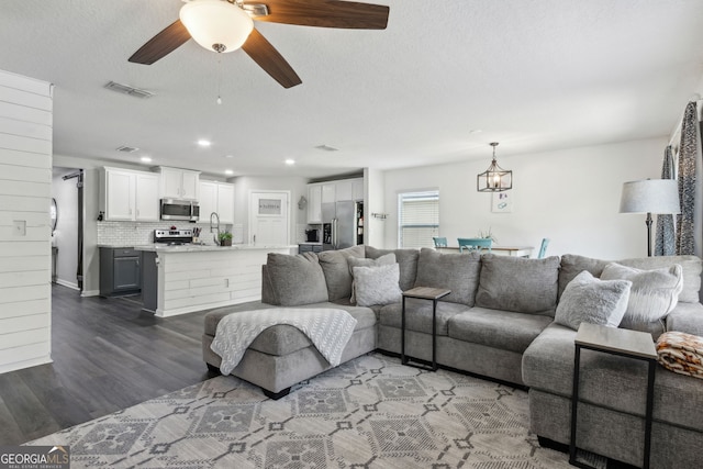 living room with visible vents, a ceiling fan, a textured ceiling, recessed lighting, and wood finished floors