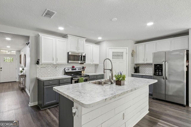 kitchen featuring dark wood finished floors, visible vents, appliances with stainless steel finishes, light countertops, and a sink