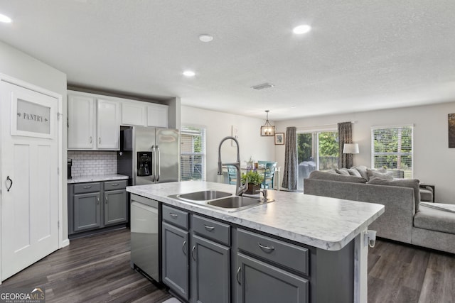 kitchen with open floor plan, appliances with stainless steel finishes, a sink, and gray cabinetry