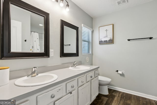 bathroom featuring a sink, visible vents, toilet, and wood finished floors