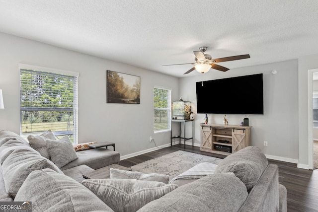 living room with dark wood-type flooring, ceiling fan, baseboards, and a textured ceiling