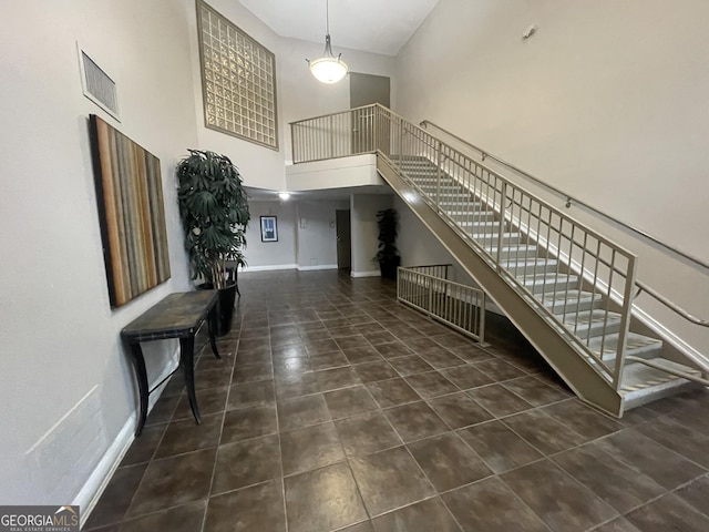 entrance foyer with baseboards, tile patterned flooring, a towering ceiling, and stairs