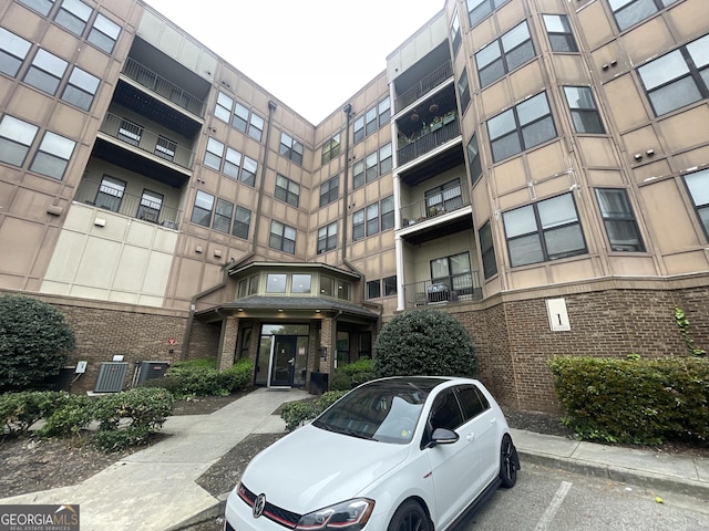 view of building exterior featuring central air condition unit and uncovered parking