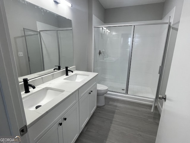 full bath with toilet, a stall shower, wood finished floors, and a sink