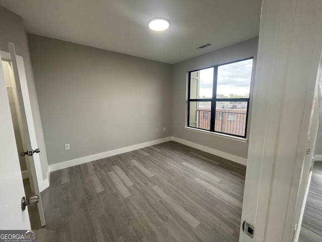 empty room with visible vents, baseboards, and dark wood finished floors