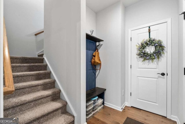 foyer featuring wood finished floors, baseboards, and stairs