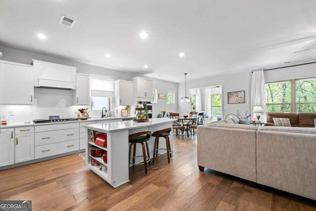 kitchen featuring open floor plan, black cooktop, white cabinetry, and a kitchen island