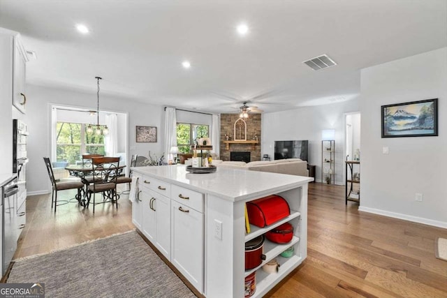 kitchen featuring visible vents, white cabinets, open shelves, ceiling fan, and a fireplace