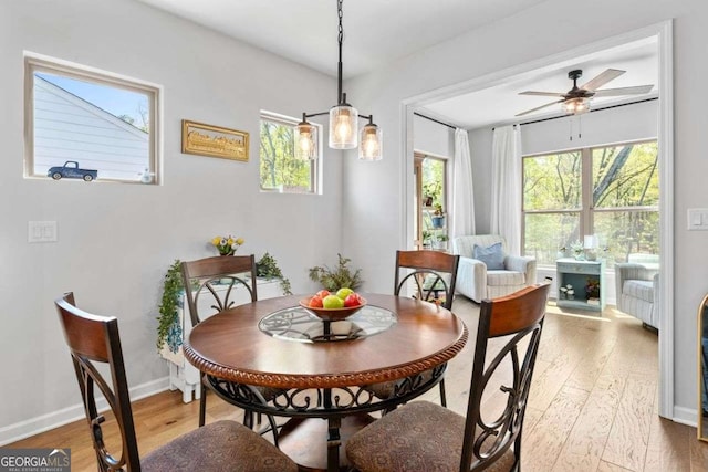 dining area featuring light wood-type flooring, baseboards, and a ceiling fan