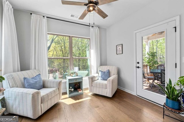 sitting room featuring wood finished floors, a ceiling fan, and plenty of natural light