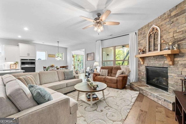 living area featuring a fireplace, a ceiling fan, visible vents, recessed lighting, and wood finished floors