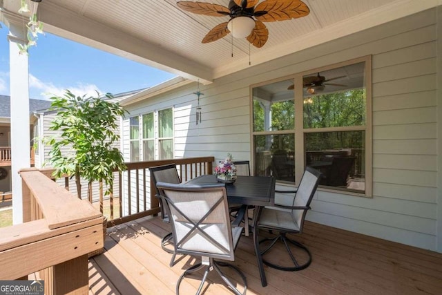wooden deck with outdoor dining space and ceiling fan