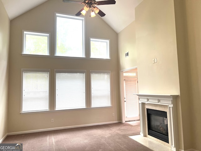 unfurnished living room featuring ceiling fan, carpet floors, high vaulted ceiling, a fireplace with flush hearth, and baseboards
