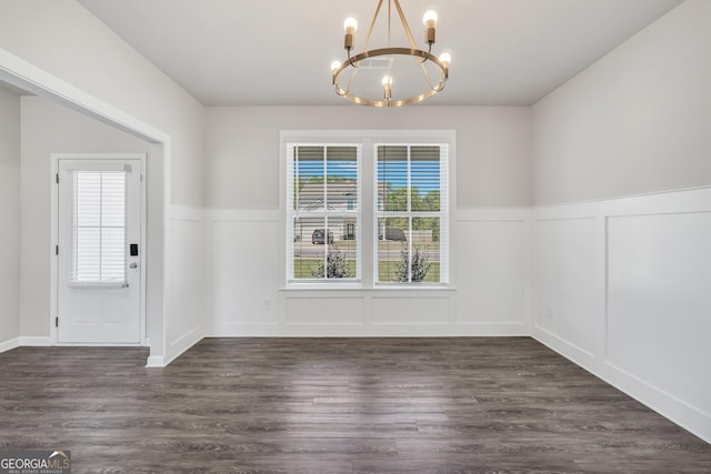 unfurnished dining area with a decorative wall, an inviting chandelier, and a wainscoted wall