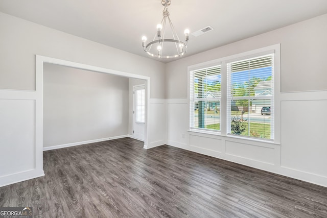 unfurnished dining area with a chandelier, dark wood-type flooring, visible vents, and a wainscoted wall